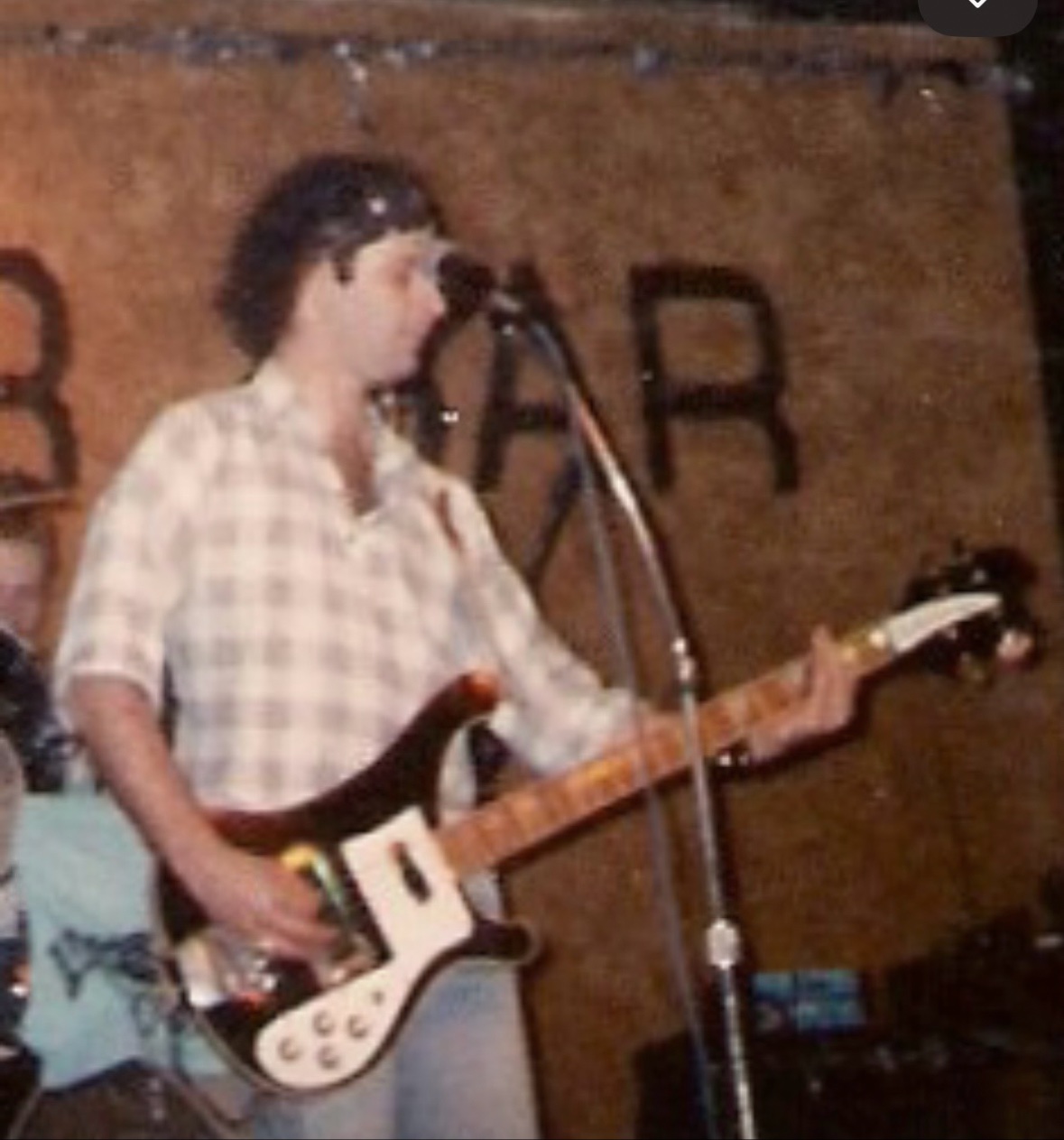 Vintage photo of a young Greg Wiggs playing guitar on stage